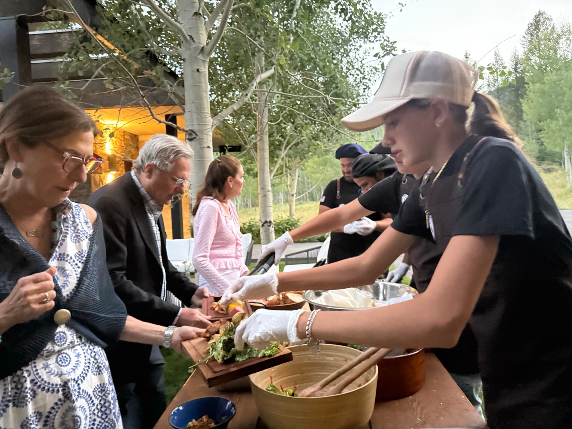 A member of the family serving guests fresh from the grill at an evening gathering